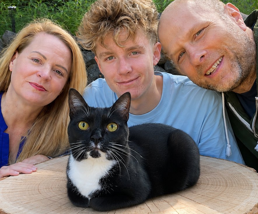 The Maxi's Multi family gathered behind Maxi, their tuxedo cat, who is lying on a wood slab